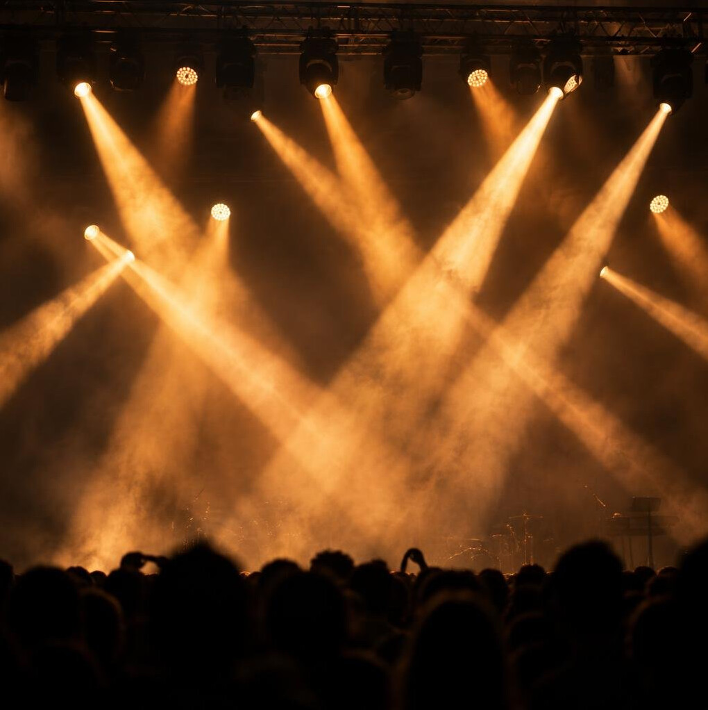 Stage lights and haze above a live audience
